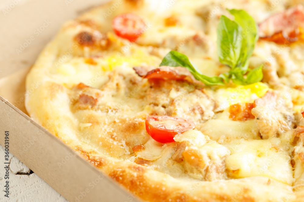 Close up of pizzas with variety of toppings and cheese in cardboard take out boxes with open lid on wooden table Close up of pizzas with variety of toppings and cheese in cardboard take out boxes with open lid on wooden table