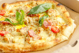 Close up of pizzas with variety of toppings and cheese in cardboard take out boxes with open lid on wooden table