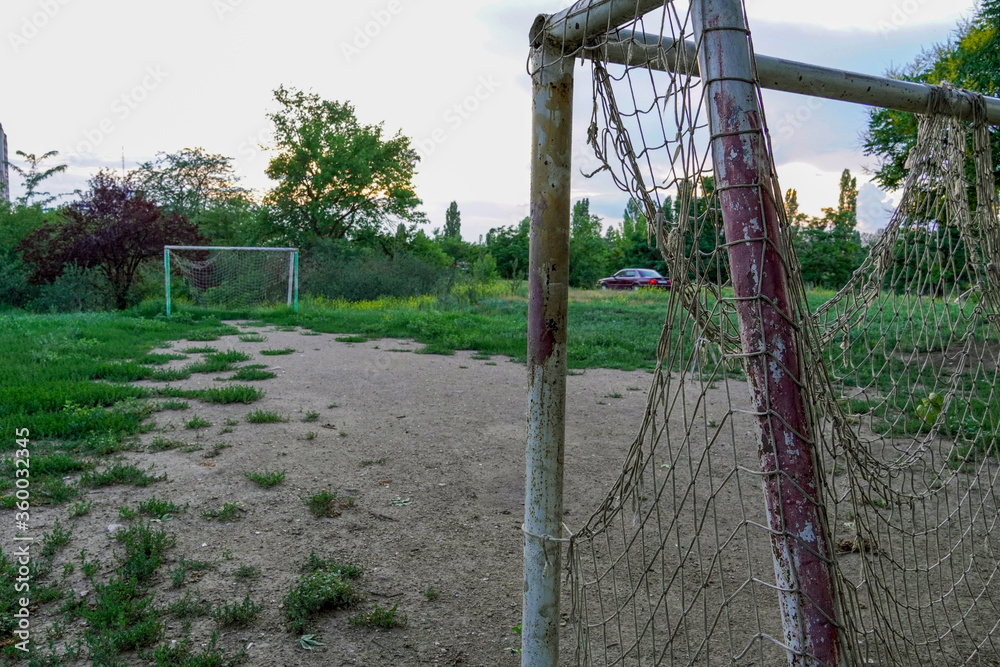 abandoned football field, goal with a torn net in a vacant lot