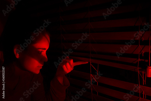 Konstfotografi Curious young woman looking out the window