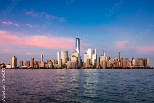 Downtown Manhattan skyline at pink hour with light cirrus clouds as seen across the Hudson river from Exchange Place in Jersey City, New Jersey on June 21, 2020. © Val