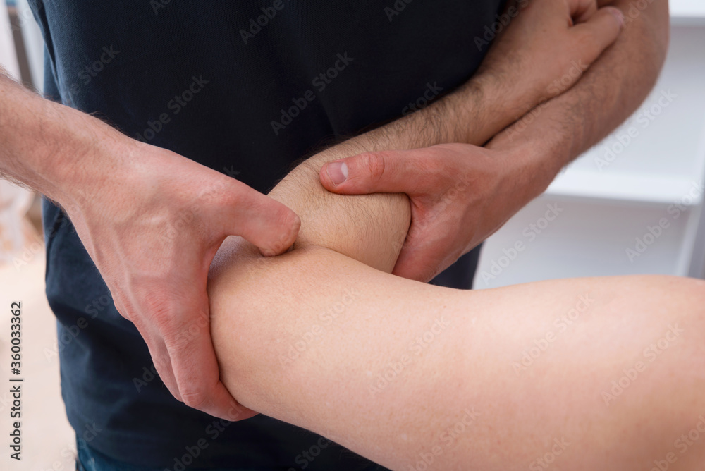 Male Physical therapist is pressing on one mans elbow making deep massage. Male Physical therapist is pressing on one mans elbow making deep massage.