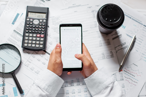 Businessman in the office of the table with graphics holding a phone