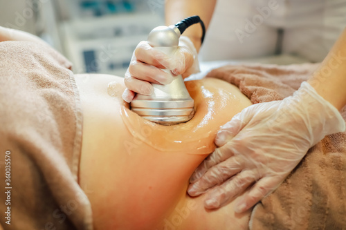 Hands of a person doing a cellulite removal procedure on woman's stomach
