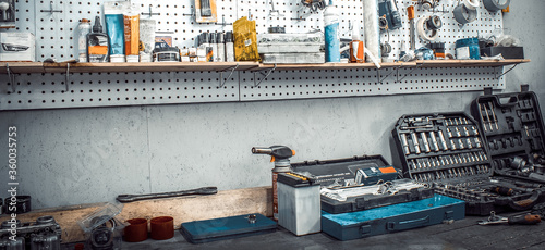 Moto workshop with hand mechanic tools kit. Workbench with sets of keys box, screwdrivers, electrical tape, on wall Table with motorcycle parts, vise. Workspace for auto mechanic. Banner for web site