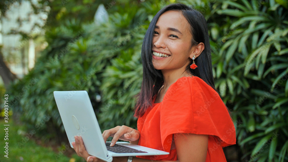 Young Indonesian girl with a laptop in hand in the park. Young Indonesian girl with a laptop in hand in the park.