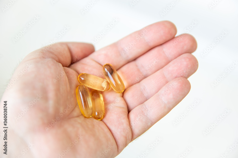 Yellow capsules of vitamin omega 3 in your hand. Biologically active additive. Fish oil in tablets. Medical support and treatment. Yellow capsules of vitamin omega 3 in your hand. Biologically active additive. Fish oil in tablets. Medical support and treatment.
