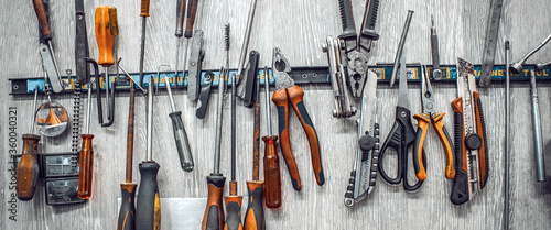 Maintenance station, motorcycle repair, mechanical equipment, tools in workshop. Manual machine tool on wall in garage. Knives, pliers, screwdrivers, scissors wrenches close-up. Banner for web site
