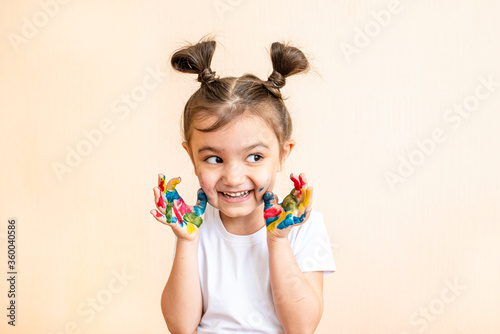  joyful little girl with painted hands. the child joyfully shows his palms painted with paints. painted children's palms
