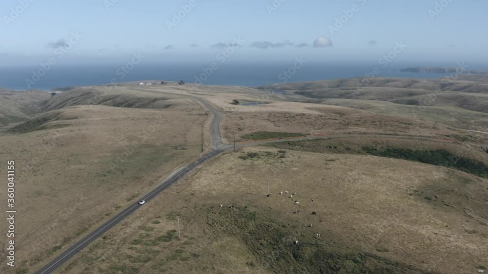 Aerial drone reveal shot of car driving on highway with panoramic ocean view Aerial drone reveal shot of car driving on highway with panoramic ocean view