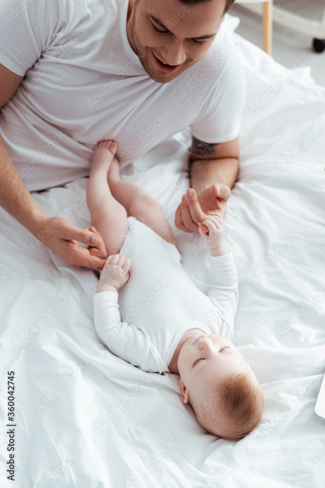 overhead view of happy father touching hands of adorable little son