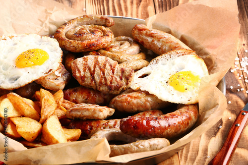 bavarian sausage plate with potatoes and fried egg. Grilled sausages closeup. Top view with copy space Appetizing beer snacks set.