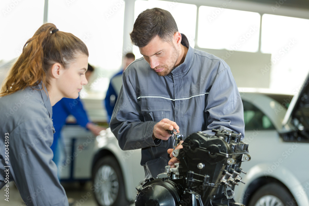 female auto mechanic learning to fix an engine