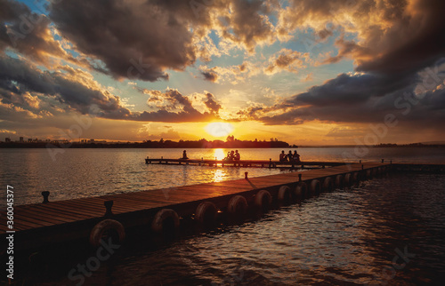Silhouette of people watching the sunset from the wood pier in Ermida Dom Bosco, Brasília, Distrito Federal, Brazil. Dramatic sunset at Lago Paranoá. photo