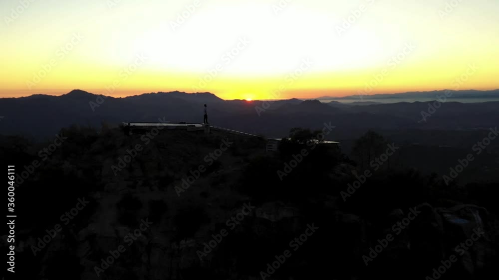 Aerial tilt reveal shot of male silhouette on rooftop in Malibu sunset Aerial tilt reveal shot of male silhouette on rooftop in Malibu sunset