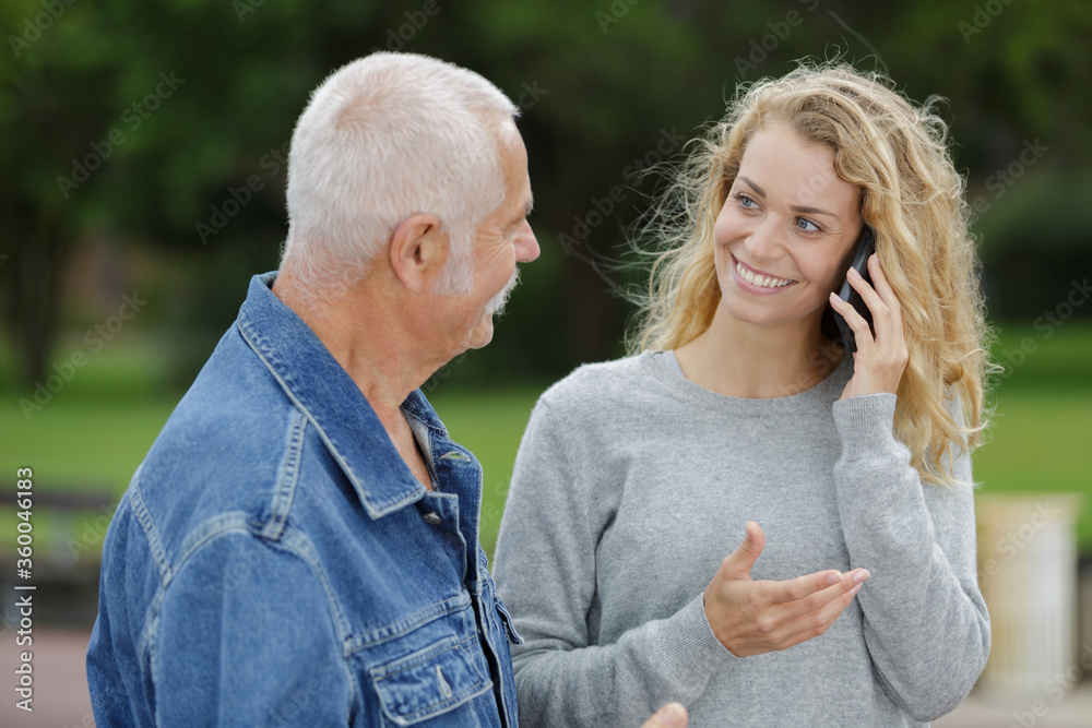 smiling young woman on mobile phone with senior father smiling young woman on mobile phone with senior father