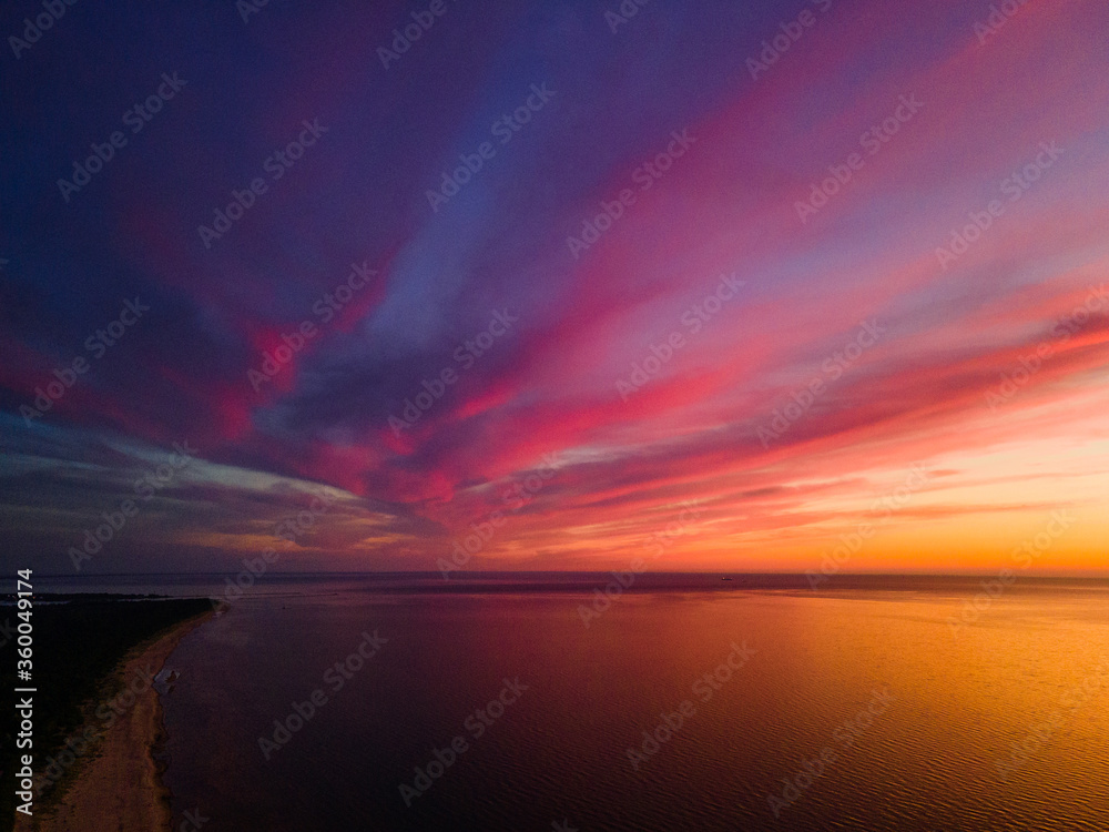 Fototapeta premium Epic vivid sunset or sunrise aerial view with sun setting down to the right. Amazing cloudscape