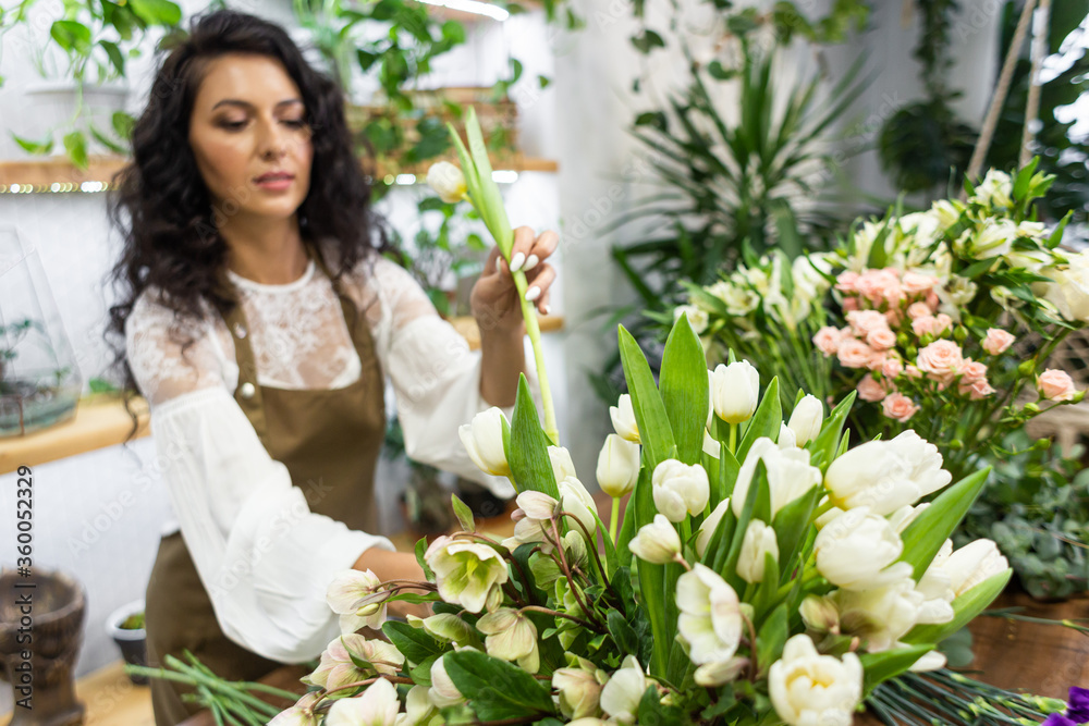 Attractive young woman florist is working in a flower shop. Attractive young woman florist is working in a flower shop.