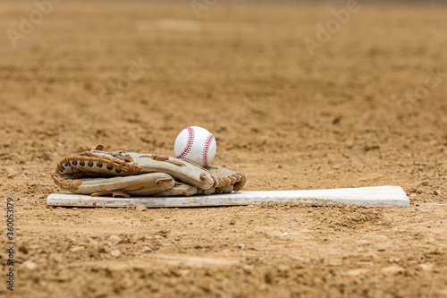 Canvas Print Baseball glove and ball sitting on pitching mound rubber on infield of baseball field