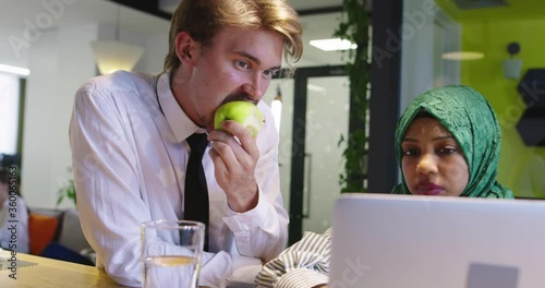 Black woman with hijab meeting business man in casual startup office, man ieating apple on meeting photo