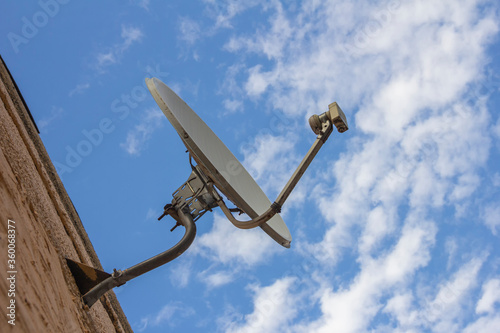 Satellite dish antenna on the old house wall or cloudy sky background