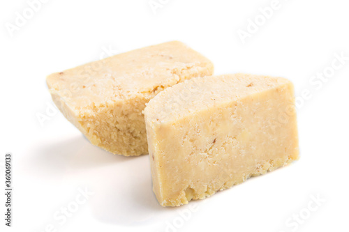Piece of cheddar cheese isolated on white background. Side view.
