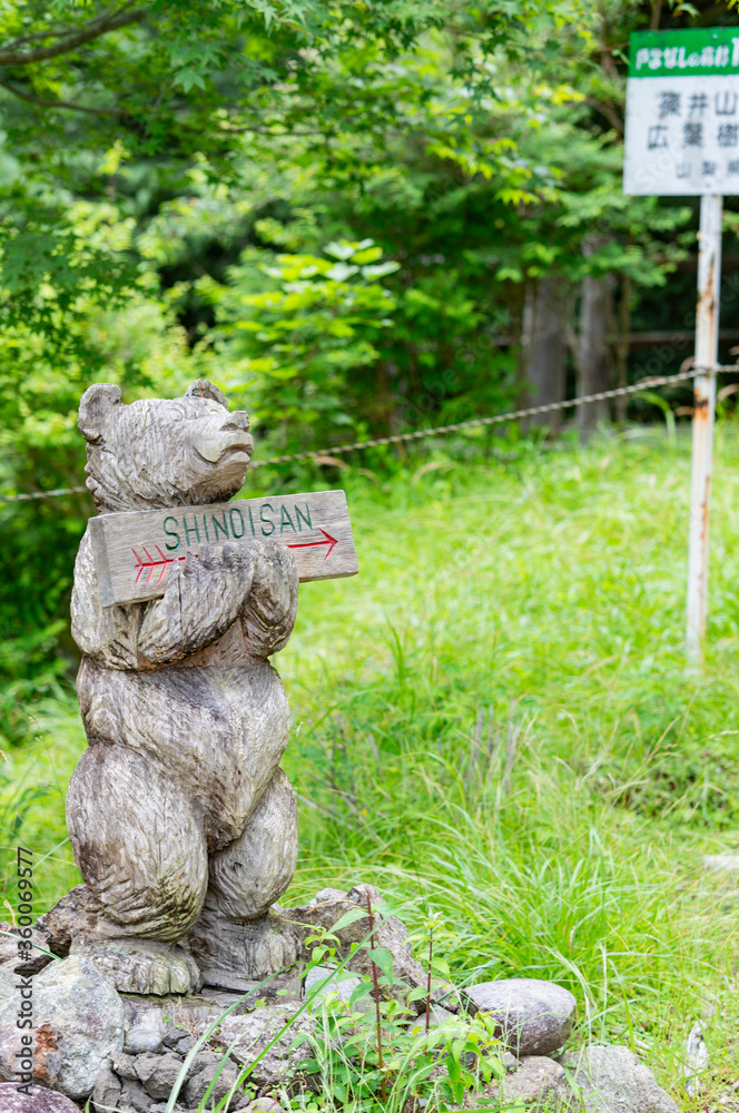 Obraz premium 篠井山登山口にある案内看板の木彫りの熊