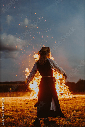 Folk girl dancing by midsummer holidays night fire in Latvia