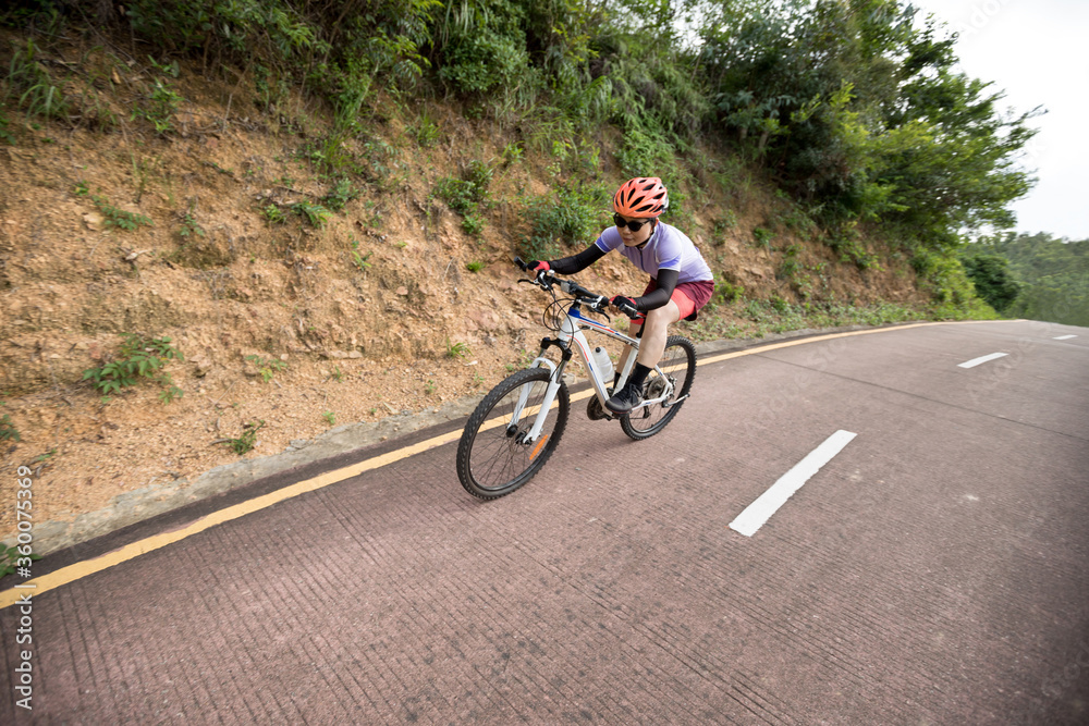 Woman riding bike down a slope with fast speed on mountain trail Woman riding bike down a slope with fast speed on mountain trail