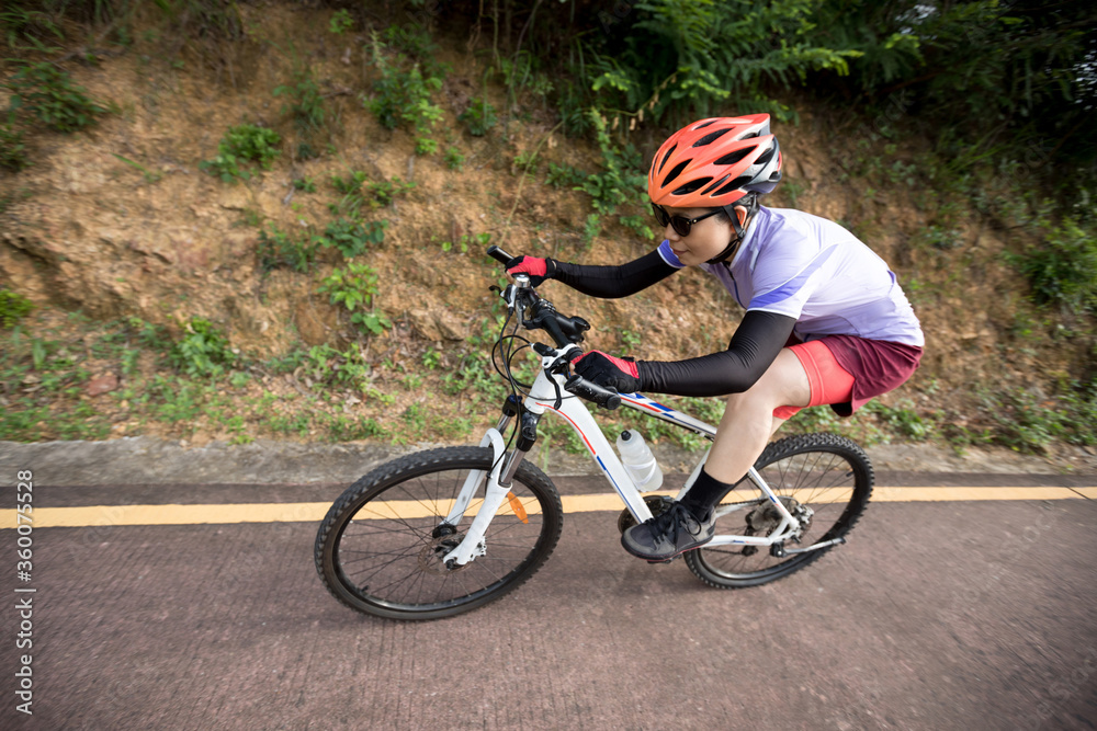 Woman riding bike down a slope with fast speed on mountain trail