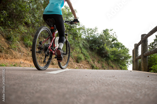 Woman riding bike on sunny mountain trail