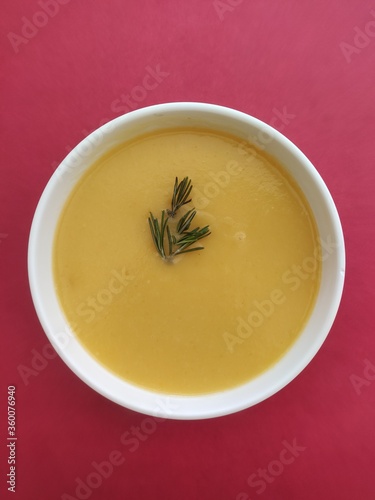 bowl of yellow vegetable soup on red background 