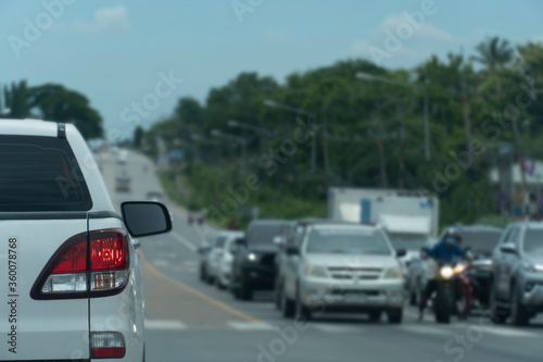 Transportation of pick up car white color on the road. Open brake light. Heading to travel or work. And residence in front. Stop waiting for traffic signals at an intersection. © thongchainak