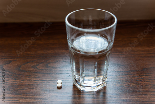 pills and glass of water on a wooden table
