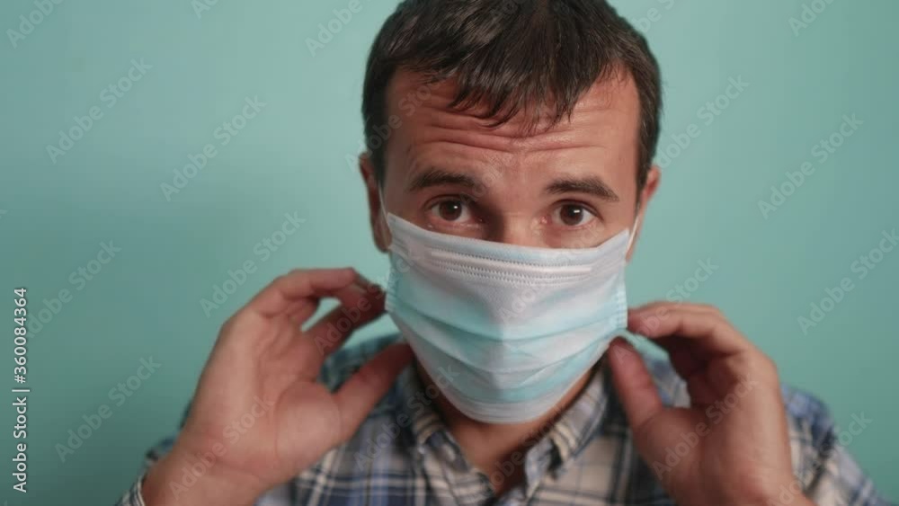 man wear puts on protective mask a indoor portrait. epidemic corona outbreak concept. male 37 years old brunette in blue medical mask isolated. Coronavirus disease. dad teamwork self-isolation in home man wear puts on protective mask a indoor portrait. epidemic corona outbreak concept. male 37 years old brunette in blue medical mask isolated. Coronavirus disease. dad teamwork self-isolation in home