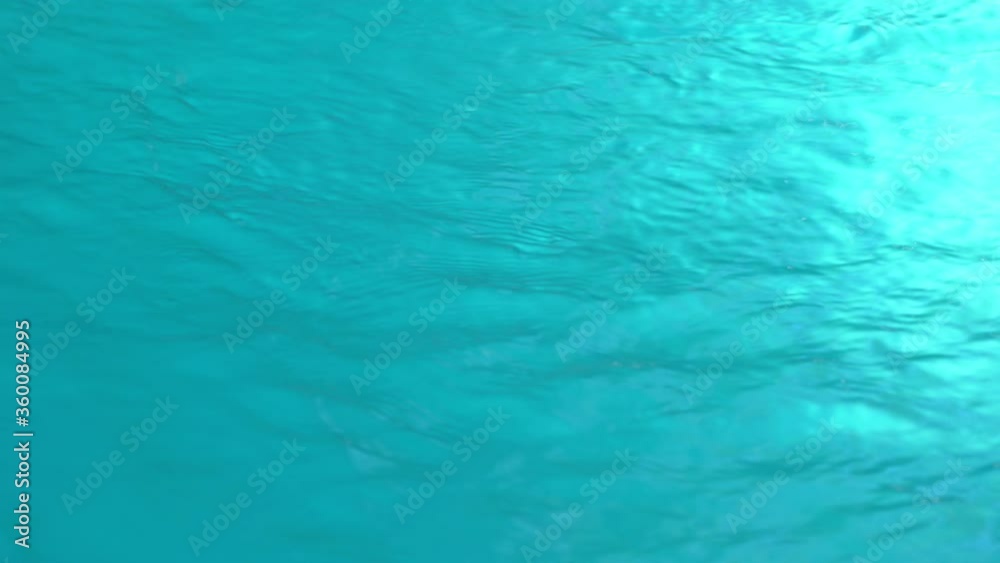 Beautiful sparkling shiny texture of blurry blue water with sun reflected on surface of water Beautiful sparkling shiny texture of blurry blue water with sun reflected on surface of water
