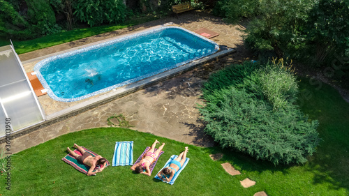 Happy family relaxing by swimming pool, aerial drone view from above of parents and kids have fun on vacation, family weekend on resort 