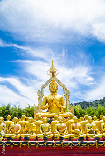 Row of disciple statues surrounding big buddha statue.