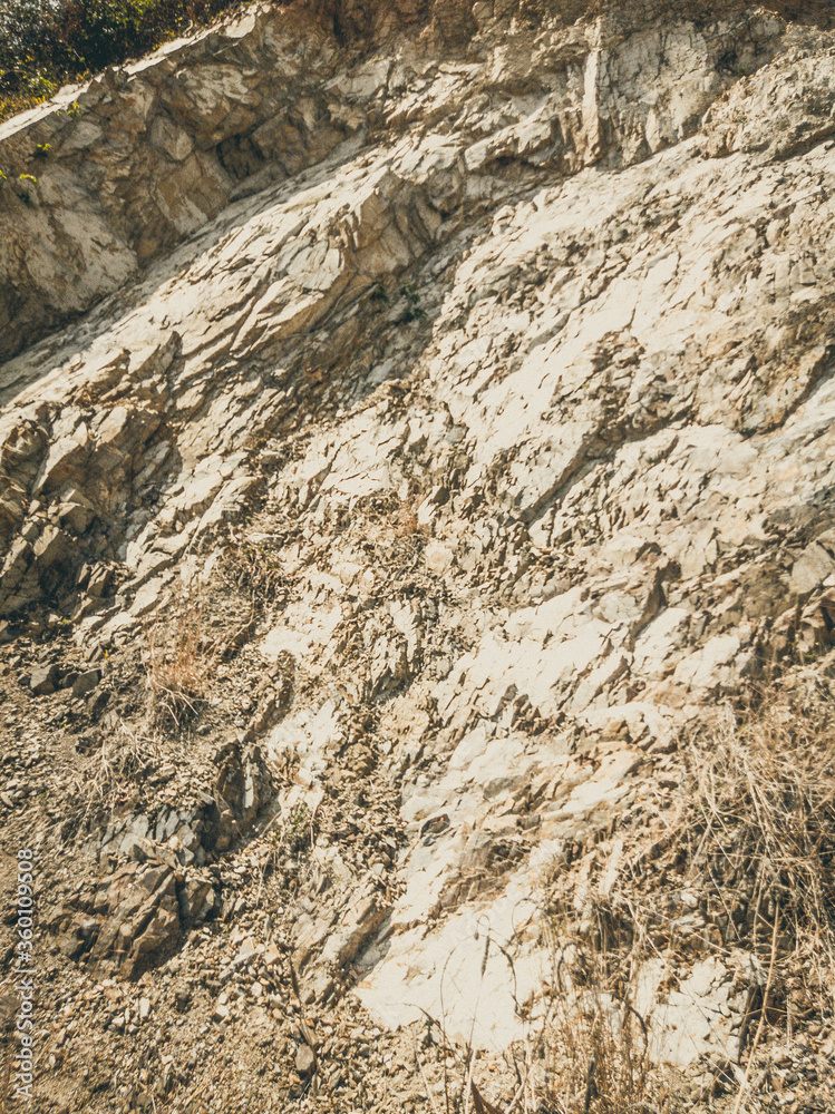 Natural background. Closeup edged shabby cliff cracks. Gray-brown stone rock texture of mountains. Vintage and faded matt style colour in tinted photo. Concept of geolog, mountaineering or hard work