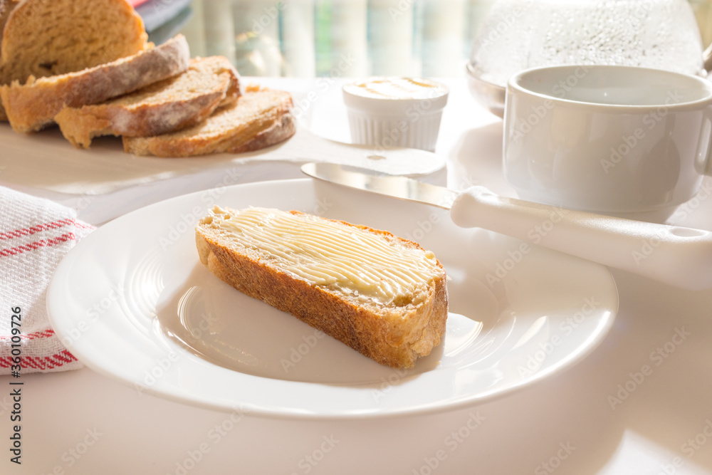 Mesa com Café da Manha: Pão Integral com manteiga, chícara de café, bule com café, toalha vermelha xadrez, pão integral fatiado sobre tábua branca, manteiga no ramequim, pão com manteiga Ponto de vist Mesa com Café da Manha: Pão Integral com manteiga, chícara de café, bule com café, toalha vermelha xadrez, pão integral fatiado sobre tábua branca, manteiga no ramequim, pão com manteiga Ponto de vist
