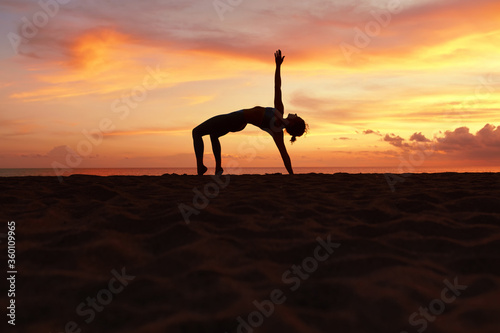 Yoga Poses. Woman Practicing Half Moon Asana On Ocean Beach. Female Silhouette Standing In Ardha Chandrasana At Beautiful Sunset. Yoga As Exercise For Lifestyle.
