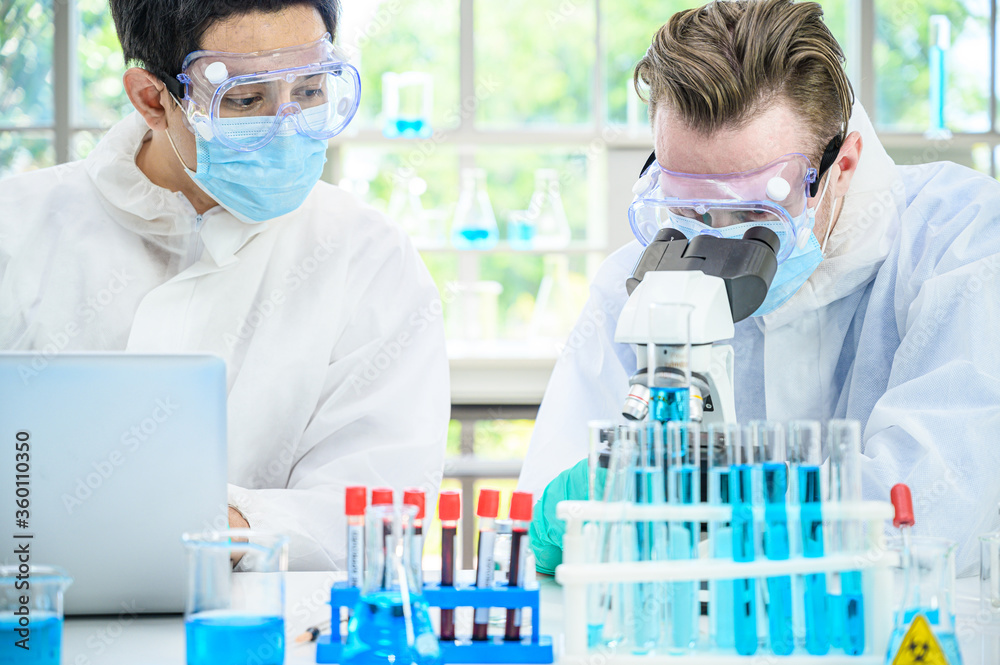Couple male scientist wearing protection suit working with many lab equipment and computer laptop for research vaccine at laboratory. Couple male scientist wearing protection suit working with many lab equipment and computer laptop for research vaccine at laboratory.