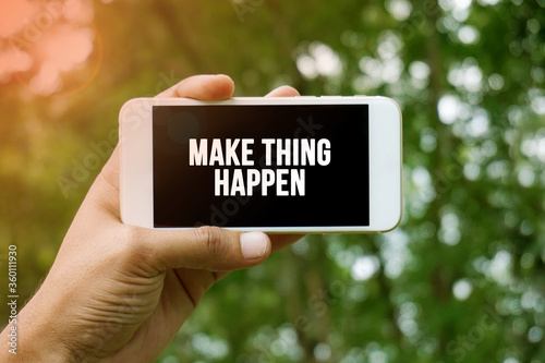 MAKE THING HAPPEN word on smartphone with bokeh in background © dzakymurad