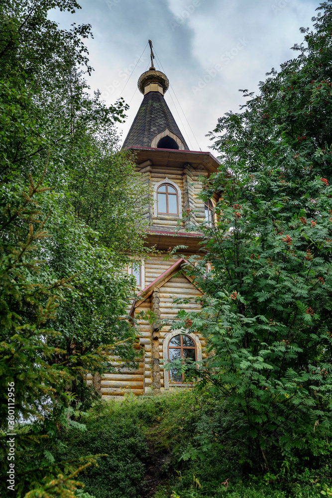 Old Karelian wooden church in the thickets of trees. Vertical.
