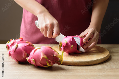 Woman cutting dragon fruit or pitaya on wooden board, Tropical fruit