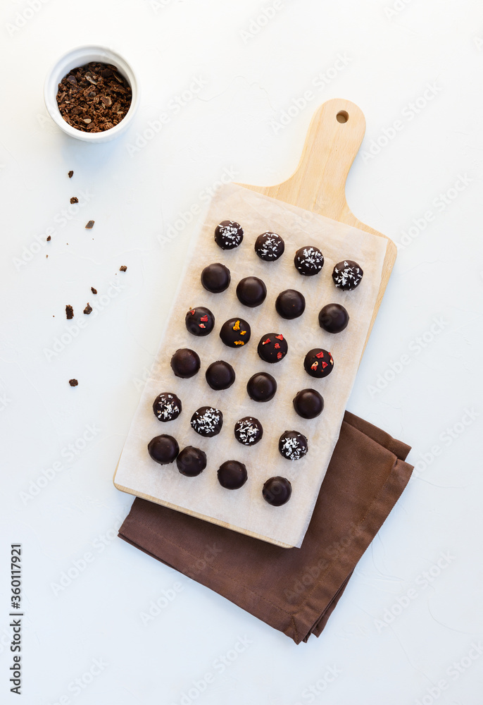 Homemade sweets made from oatmeal, walnuts and raisins, coated with dark chocolate, sublimated berries and coconut flakes on a wooden board. Sugar free, gluten, lactose. Homemade sweets made from oatmeal, walnuts and raisins, coated with dark chocolate, sublimated berries and coconut flakes on a wooden board. Sugar free, gluten, lactose.