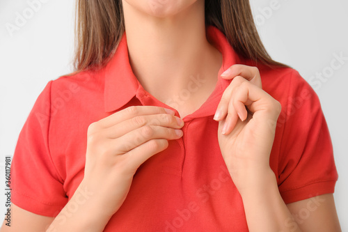 Beautiful young woman in stylish polo shirt on light background