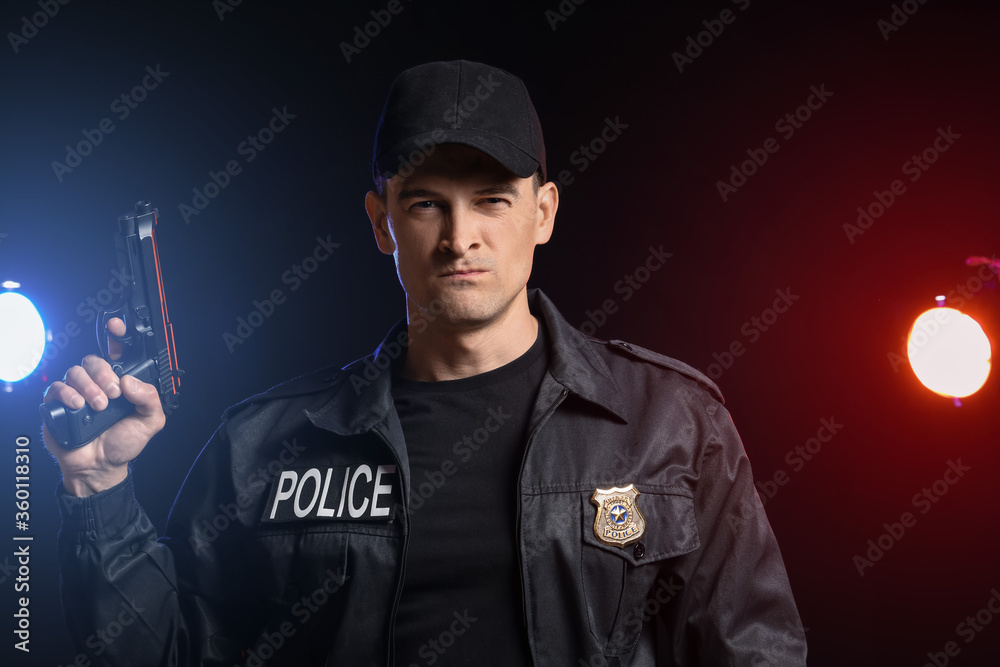 Obraz premium Aggressive police officer with gun on dark background