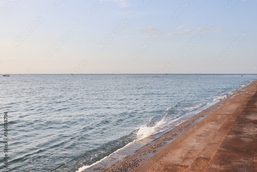 Beautiful morning view of the open freshness blue sky and sea with small and soft white wave hit the concrete stairs shoreline in summer for travel business background.
