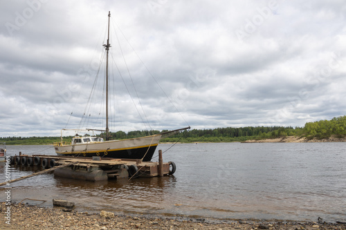 Photo of an old sailing ship on the river bank.